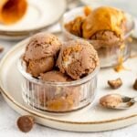 Chocolate and peanut butter ice cream scoops in glass bowls, with peanut butter cups and a spoon on the side—an irresistible No Churn Chocolate Peanut Butter Cup Ice Cream treat for any fan of ice cream with peanut butter cups.