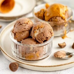 Chocolate and peanut butter ice cream scoops in glass bowls, with peanut butter cups and a spoon on the side—an irresistible No Churn Chocolate Peanut Butter Cup Ice Cream treat for any fan of ice cream with peanut butter cups.