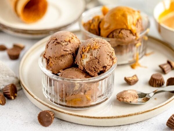 Chocolate and peanut butter ice cream scoops in glass bowls, with peanut butter cups and a spoon on the side—an irresistible No Churn Chocolate Peanut Butter Cup Ice Cream treat for any fan of ice cream with peanut butter cups.