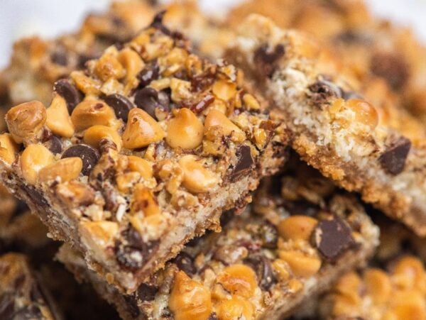 Close-up of coconut squares topped with chocolate chips, butterscotch chips, and chopped nuts—classic Hello Dolly bars for a nostalgic treat.