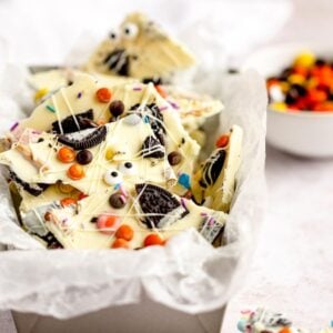White chocolate bark with Oreos, candy eyes, and colorful sprinkles makes a fun DIY Halloween candy—an easy candy bark recipe served in a tin lined with parchment paper.