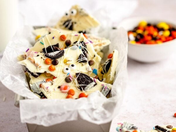 White chocolate bark with Oreos, candy eyes, and colorful sprinkles makes a fun DIY Halloween candy—an easy candy bark recipe served in a tin lined with parchment paper.