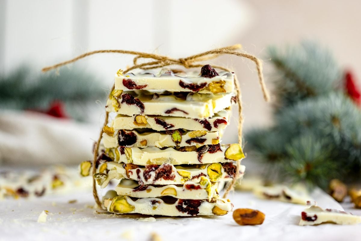 Stack of Cranberry Pistachio White Chocolate Bark tied with twine, featuring cranberries and pistachios in a festive background—an easy holiday treat recipe, perfect for gifting or enjoying like almond bark.