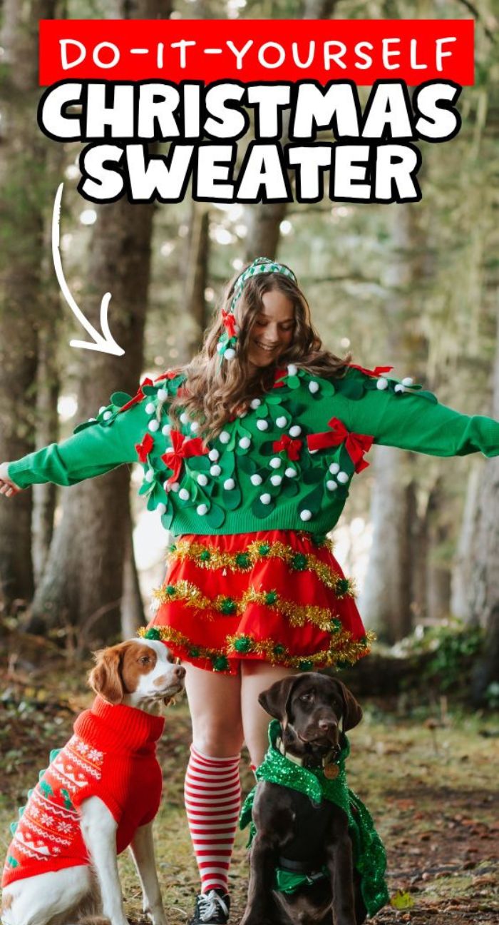 Woman in a festive DIY Christmas sweater—made using scissors or Cricut—poses in the woods with two dogs wearing holiday sweaters, ready to inspire you to make your own ugly Christmas sweater for your next party.