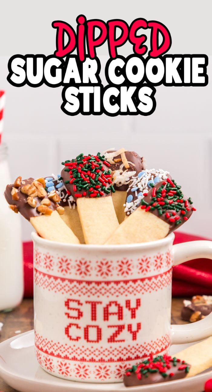 A mug labeled "Stay Cozy" holds Christmas cookie sticks dipped in chocolate and adorned with festive sprinkles and nuts—perfect for your next cookie exchange.