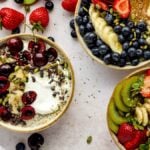 Three smoothie bowls topped with fruits like banana, strawberry, kiwi, blueberries, and seeds on a light surface—perfect inspiration for your own Oatmeal Breakfast Bowl.