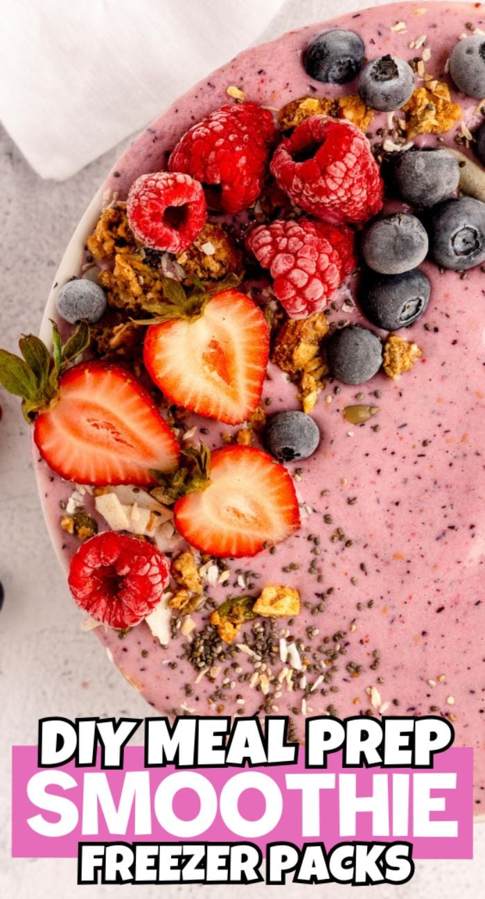A smoothie bowl topped with strawberries, raspberries, blueberries, and granola with text: “DIY Meal Prep Smoothie Freezer Packs—make ahead smoothie mix for easy mornings.”.