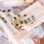 Watermelon boba popsicles with black seeds rest on ice cubes, surrounded by fresh watermelon slices.