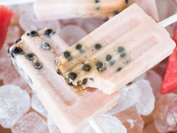 Watermelon boba popsicles with black seeds rest on ice cubes, surrounded by fresh watermelon slices.