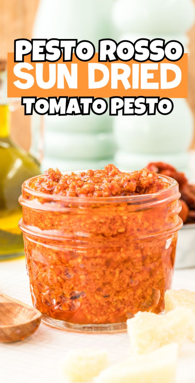 A glass jar filled with sun dried tomato pesto, an easy pasta sauce, with cheese and olive oil in the background.