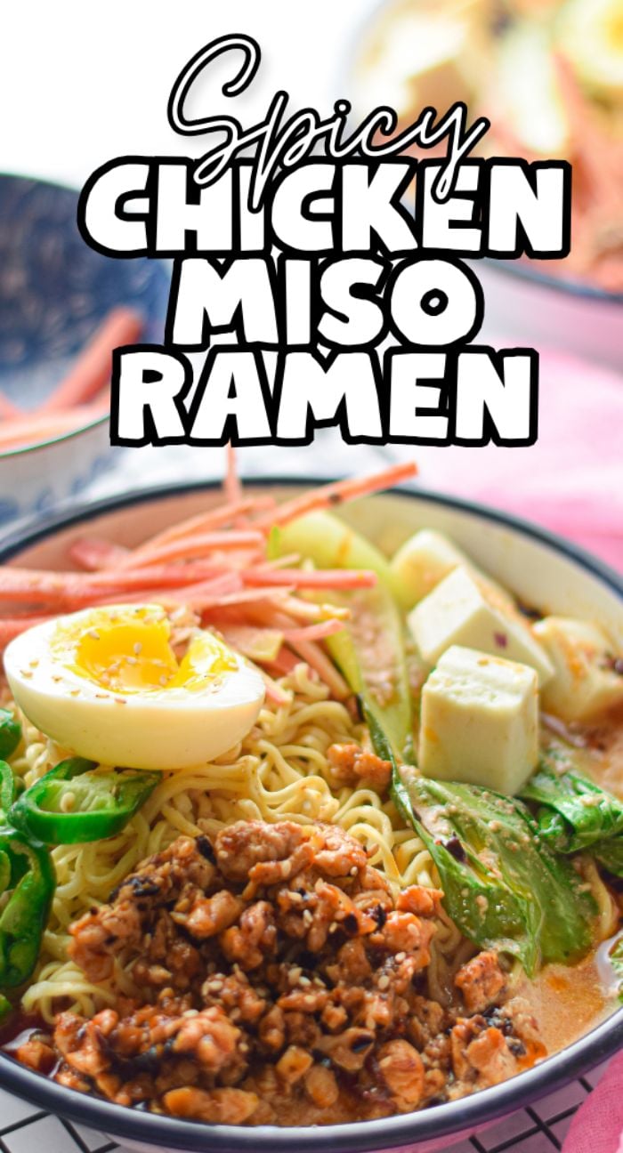 Bowl of ramen with chicken and tofu, topped with soft-boiled egg, vegetables, and sliced green chili in a spicy miso broth.