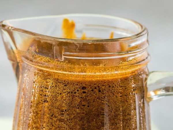 Close-up of a glass pitcher filled with frothy dalgona coffee on a light background, perfect alongside homemade unagi or as a refreshing pairing with sauce for seafood.