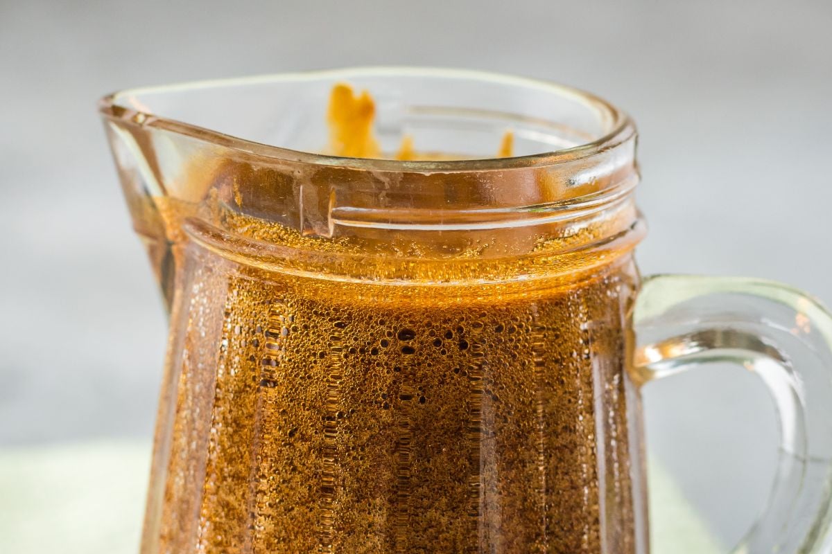 A glass pitcher filled with frothy brown liquid, possibly homemade Eel Sauce (Unagi Sauce), with foam clinging to the rim—perfect as a sauce for seafood.