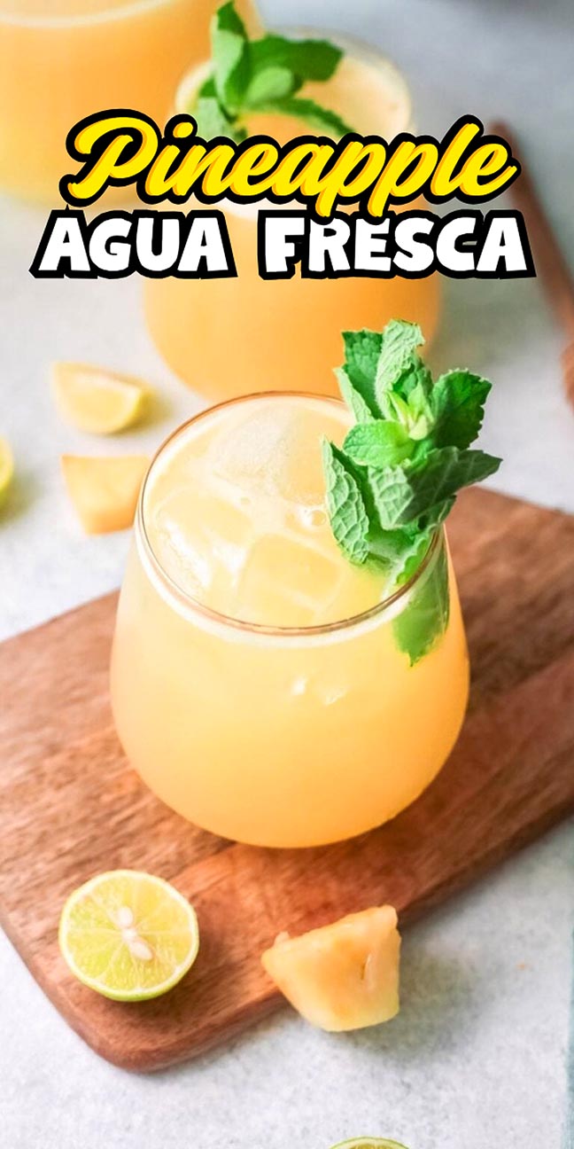Glass of pineapple agua fresca garnished with mint on a wooden board.