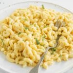 A plate of creamy mac and cheese garnished with herbs, with a fork resting on the side—perfect for anyone craving comfort food or looking for a quick macaroni Instant Pot recipe.