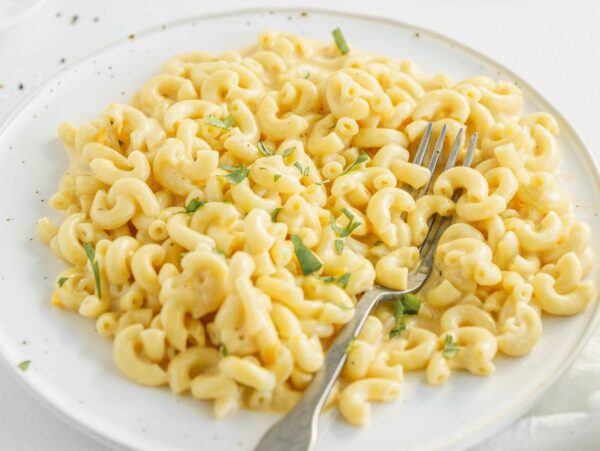 A plate of creamy mac and cheese garnished with herbs, with a fork resting on the side—perfect for anyone craving comfort food or looking for a quick macaroni Instant Pot recipe.