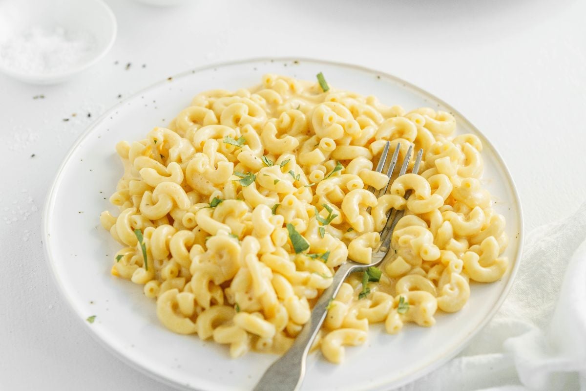 A plate of creamy Instant Pot macaroni and cheese garnished with herbs, with a fork resting on the side—an easy instant pot pasta recipe perfect for any meal.