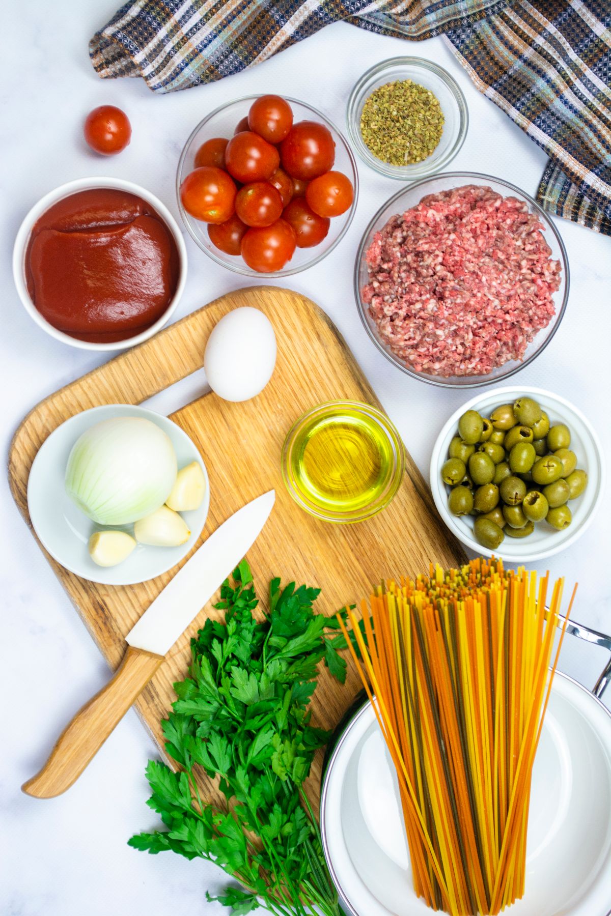 Ingredients for Mediterranean spaghetti and meatballs: ground meat, pasta, tomatoes, onion, garlic, egg, olives, oil, and herbs—perfect for an easy one pot pasta meal.
