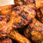 Close-up of several seasoned, grilled chicken drumsticks garnished with herbs—delicious served alongside homemade firecracker ranch dressing.