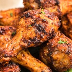 Close-up of several seasoned, grilled chicken drumsticks garnished with herbs—delicious served alongside homemade firecracker ranch dressing.