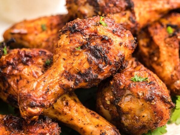 Close-up of several seasoned, grilled chicken drumsticks garnished with herbs—delicious served alongside homemade firecracker ranch dressing.