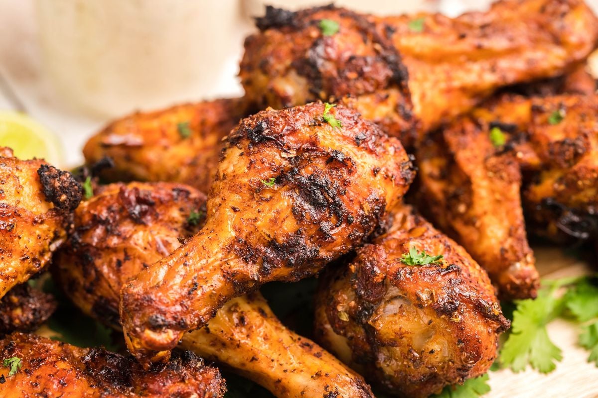 Grilled chicken drumsticks with a crispy, seasoned coating, garnished with herbs and served on a plate—delicious when paired with homemade firecracker ranch dressing for an extra kick.