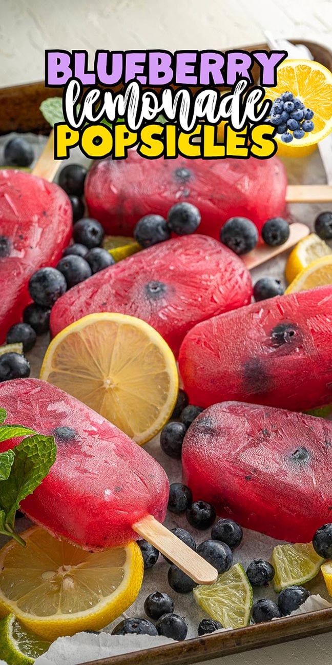 Blueberry lemonade popsicles with fresh berries, lemon slices, and mint leaves.