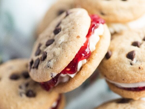 Close-up of Chocolate Chip Buttercream Sandwiches—delicious sandwich cookies filled with white cream and red jelly for the perfect treat.