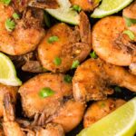 Cooked, seasoned smoked jerk shrimp garnished with cilantro and lime wedges, arranged closely together—perfect for anyone craving a delicious smoked jerk shrimp recipe.