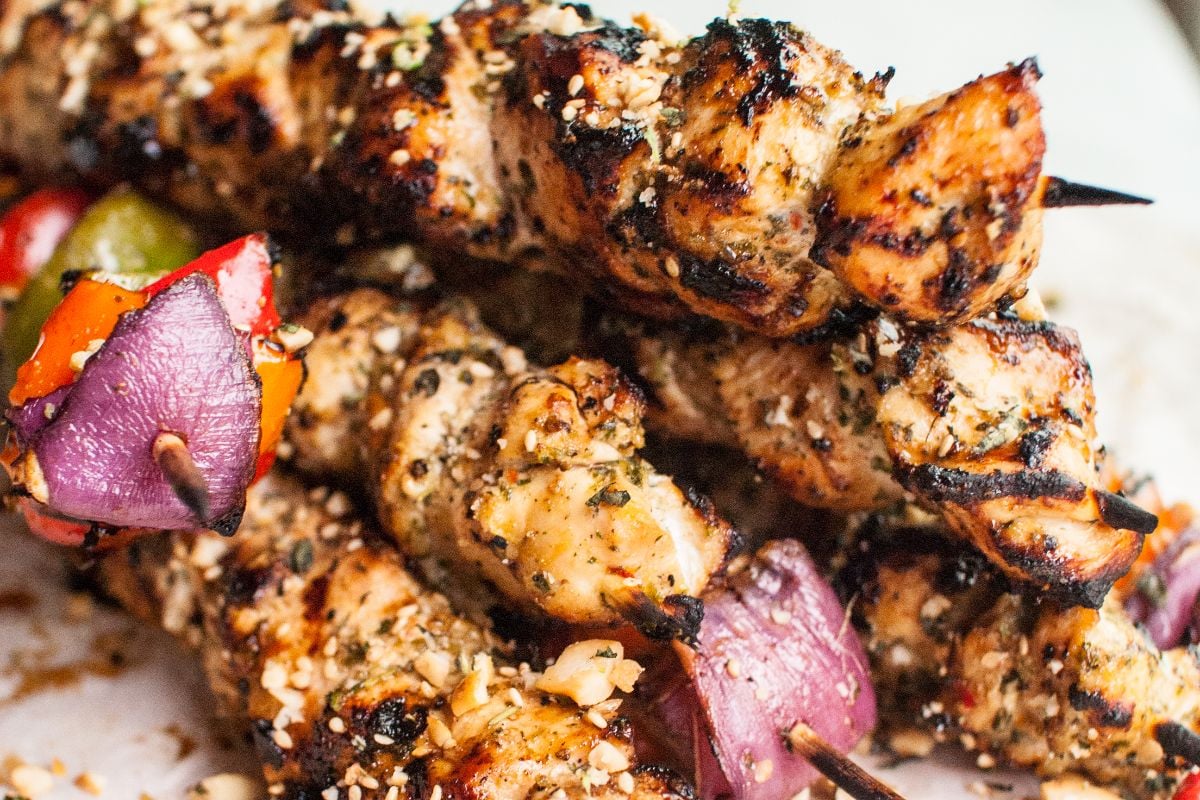 Grilled chicken and vegetable skewers with herbs and spices, featuring onions and bell peppers, served with a creamy cashew dipping sauce.