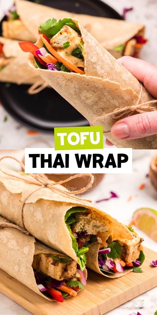 Hand holding a tofu Thai wrap filled with colorful veggies, with more wraps on a plate and a wooden surface.