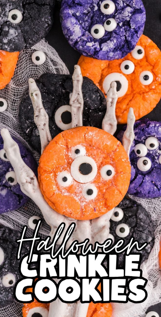 Assorted orange, black, and purple crinkle cake mix Halloween cookies with candy eyes held by a skeleton hand&mdash;easy Halloween cookie decorating ideas for spooky Halloween treats.
