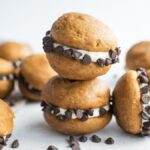 Pumpkin gobs with cream cheese whoopie pie filling and chocolate chips, stacked on a white surface—a perfect pumpkin spiced cookie recipe.
