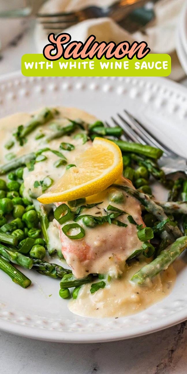 Salmon fillet with white wine sauce, asparagus, and peas, topped with a lemon slice.