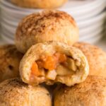 A stack of apple-filled pastry bites, one with a bite showing the spiced filling inside—these puff pastry dumplings are perfect for snacking. Try making Air Fryer Apricot Apple Dumplings for a quick and delicious twist!.