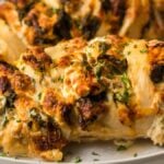 Stuffed chicken breast with herbs and melted cheese on a white plate—an irresistible air fryer chicken recipe inspired by creamy bacon chicken.