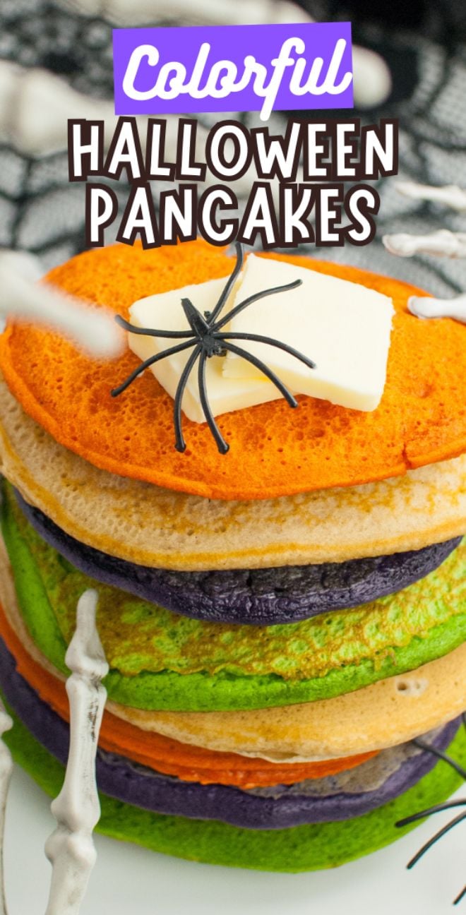 Stack of colorful Halloween pancakes—orange, green, and purple—with butter, a fake spider, and skeleton hands. Perfect Halloween party food to impress your guests! Fun idea if you want to learn how to make colourful pancakes.