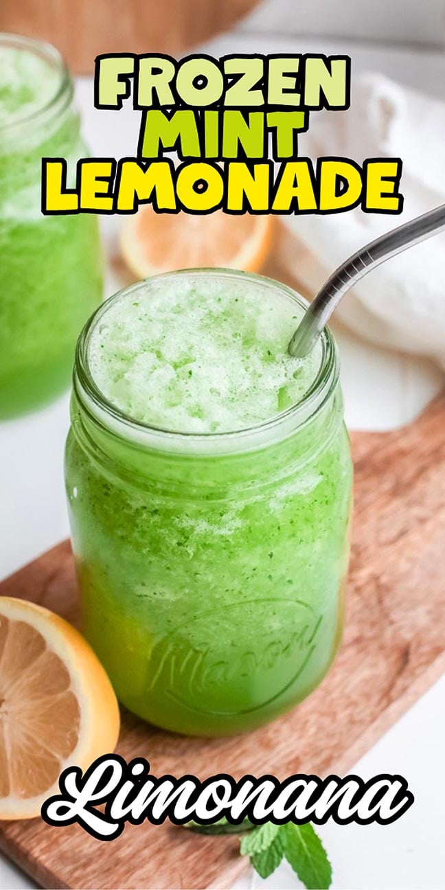 Mason jar of green frozen mint lemonade with a metal straw, lemon slice, and text reading “Frozen Mint Lemonade.”.