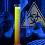 A glowing yellow liquid in a graduated cylinder with lab glassware, bones, and a biohazard sign in the background captures the essence of a fluorescent neon cocktail or glow in the dark drink perfect for Halloween.