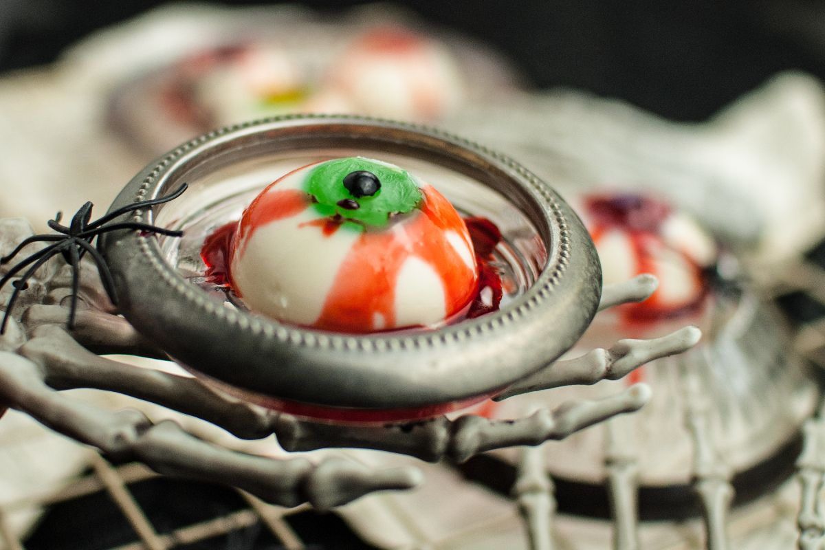 A spooky dessert that looks like eyeballs, served in a skeleton hand dish, makes for gross looking Halloween food and is perfect for Halloween party food ideas.
