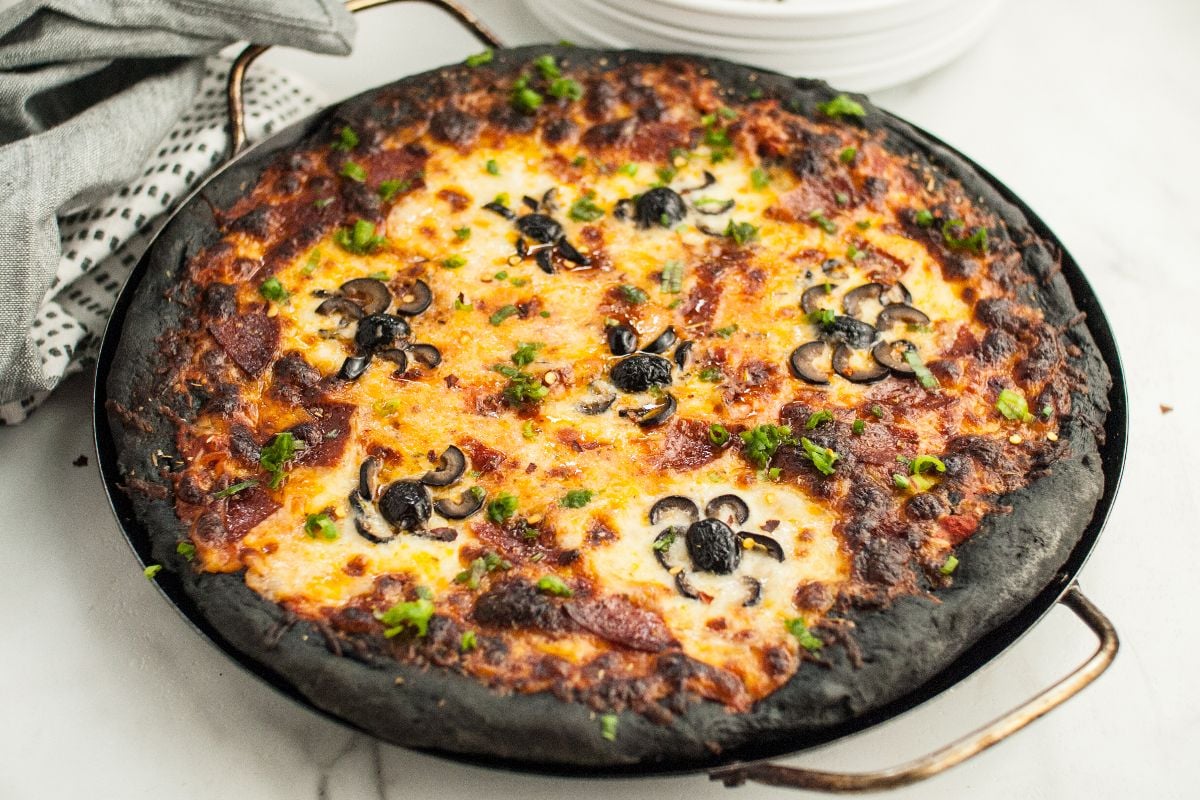Halloween Pizza with Black Crust, topped with cheese, mushrooms, green herbs, and pizza with black olive spiders, makes a spooky addition to your Halloween dinner menu for adults and kids.