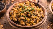 A wooden bowl of creamy instant pot wild rice and lentil casserole, garnished with fresh herbs on top.