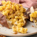 Mac & Beer Cheese in Pretzel Bowls: Creamy mac and cheese with rich beer cheese sauce for macaroni, stuffed inside a soft pretzel roll and served on a plate, ready to enjoy with every bite.