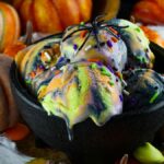Black bowl of colorful No Churn Halloween Ice Cream with sprinkles, topped with a fake spider, surrounded by pumpkins—the perfect spooky ice cream for your frozen Halloween treats.