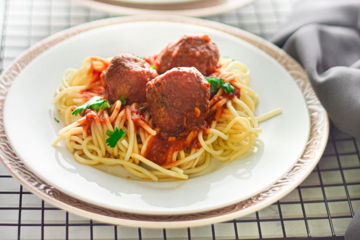 A plate of spaghetti topped with three Air Fryer Meatballs Marinara, rich tomato sauce, and parsley, served on a white plate.