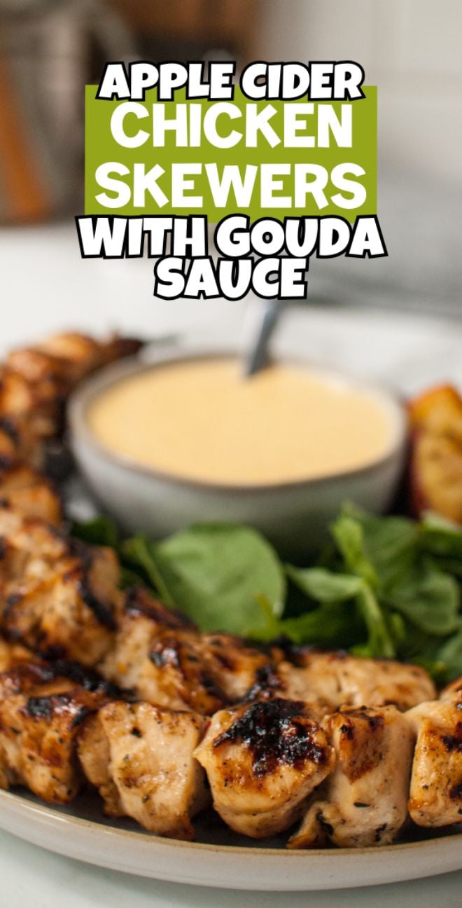 Apple Cider Chicken Skewers with Gouda Sauce served on a plate with fresh greens and a bowl of creamy Gouda Cheese Sauce in the background.