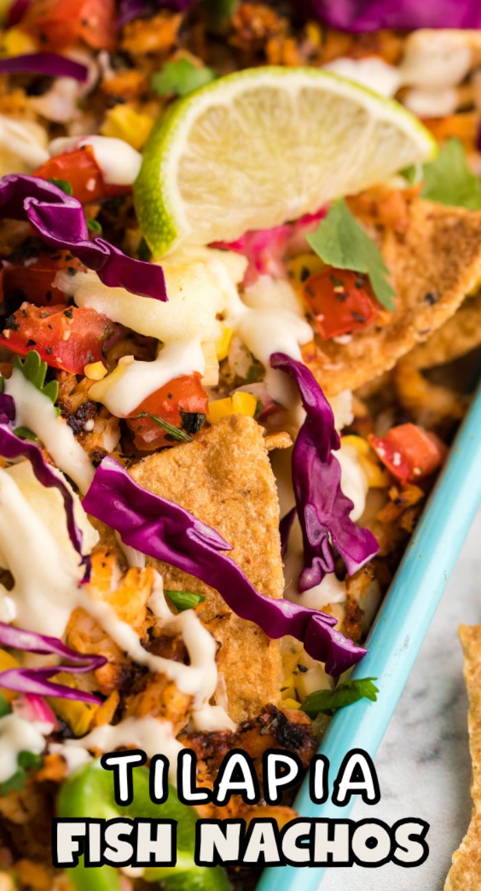 Close-up of baked loaded nachos with tilapia, cabbage, pico de gallo, sauce, and a lime slice in a blue dish—one of the best sheet pan recipes for creative topping ideas.