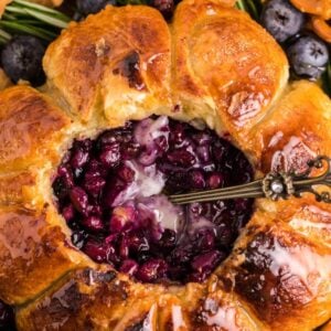 Brie and puff pastry baked in an air fryer, filled with blueberries and served with pretzels, waffle cookies, and fresh berries—this blueberry brie appetizer is perfect for any gathering.