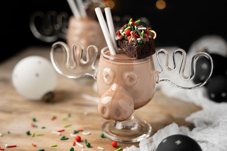 A chocolate moose in a glass with a straw on top.