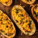 Air Fryer Twice Baked Breakfast Potatoes topped with melted cheese and fresh herbs, served on a rustic wooden surface.